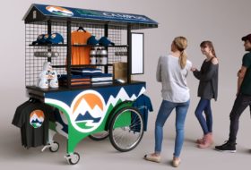 A highly mobile push cart for school apparel merchandising, wrapped in a blue, green and white vinyl wrap