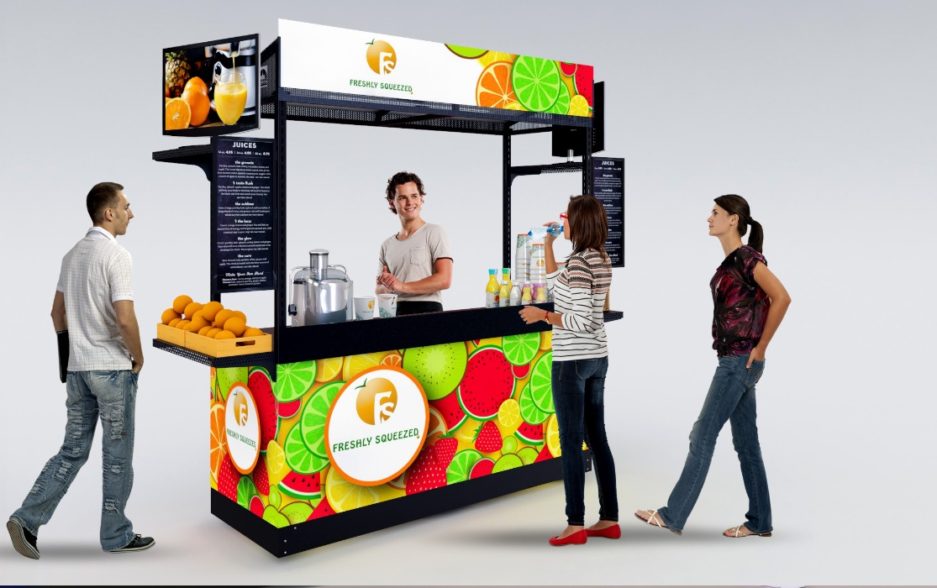 A single kiosk with a bright, fruit-colored custom graphics wrap designed for mobile beverage vending