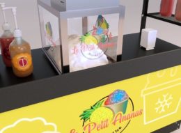 A close-up of a food cart with an eye-catching, pineapple-themed yellow graphic and contrasting black, food-safe counter.